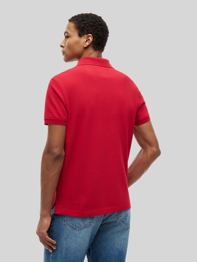 Männermodel trägt Regular Fit Poloshirt aus Baumwoll-Mix von Tommy Hilfiger in Rot, glatte Textur, Ganzkörperansicht Rückansicht. Kontext: Herren Poloshirt.