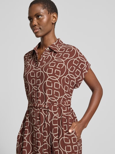 Frauenmodel trägt Midikleid aus Viskose mit Bindegürtel von Gant in Braun mit weißem Muster, Taillierter Schnitt, Hemdblusenkragen, verdeckte Knopfleiste, Nahaufnahme Oberkörper.