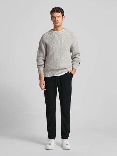 Männermodel trägt Tapered Chino mit Viskose-Anteil von Tom Tailor Denim, Optik: Unifarben, Passform: Tapered, Longline, Label-Stitching-Applikation, Tunnelzug, elastischer Bundabschluss, fixierter Beinabschluss, Gesäßtaschen, seitliche Eingrifftaschen; Ganzkörperansicht von vorne.