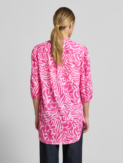 Vrouwenmodel draagt Relaxed Fit Tunika-Bluse mit floralem Allover-Print van Christian Berg Woman, puur katoen, 3/4-mouw, tuniekhals, elastische mouwboord, all-over bloemenprint in roze tinten, ruglengte maat 36: 84 cm, mouwlengte maat 36: 46 cm, ganzekörperaanzicht achterkant.
