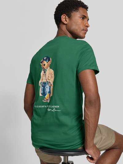 Mannelijk model draagt groen slim fit t-shirt van katoen met polo bear-print, Slim Fit T-Shirt aus reiner Baumwolle mit Polo Bear Motiv-Print von Polo Ralph Lauren, heren t-shirt van Polo Ralph Lauren, half-totale achteraanzicht.
