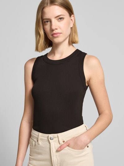 Kobiece model prezentuje top Slim Fit Top mit Rundhalsausschnitt Modell 'Olina' od Drykorn, bawełna, krój slim fit, okrągły dekolt, długość tyłu w rozmiarze S: 58 cm, kolor czarny, tekstura prążkowana, gładkie kształty, zbliżenie na górną część ciała, widok z przodu