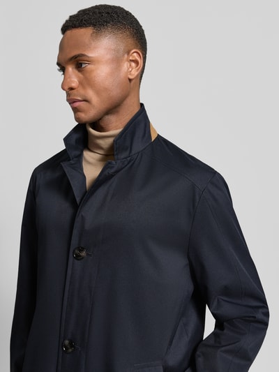 Männermodel trägt Kurzmantel im 2-in-1-Look von bugatti in Dunkelblau mit Reverskragen, Knopfleiste, Eingrifftaschen, Nahaufnahme Oberkörper