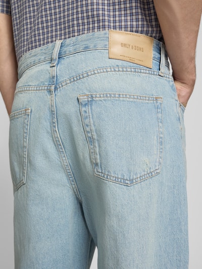 Männermodel trägt Loose Fit Jeans aus reiner Baumwolle Modell 'FADE' von Only & Sons, hellblaue Denim-Optik, Label Patch, Ganzkörperansicht Rückansicht