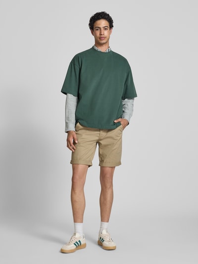 Männermodel trägt Shorts mit Gürtel Modell 'MIKE' von Redefined Rebel in Beige, Regular Fit, mit Taschen, Ganzkörperansicht von vorne.