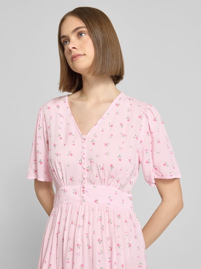 Frauenmodel trägt A-Linien Midikleid aus reiner Viskose Modell 'TALA' von Pieces, rosa mit Allover-Muster, Nahaufnahme Oberkörper.