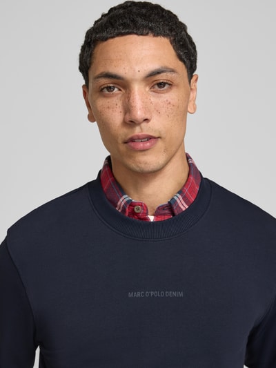 Männermodel trägt Regular Fit Sweatshirt aus reiner Baumwolle von Marc O'Polo DENIM in Dunkelblau mit glatter Textur, Nahaufnahme Oberkörper.