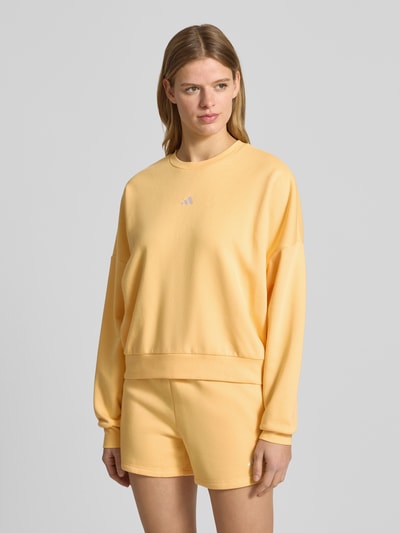 Frauenmodel trägt Sweatshirt mit Logo und Rundhalsausschnitt von adidas Sportswear, gelb, Baumwoll-Mix, Relaxed Fit, Ganzkörperansicht von vorne.
