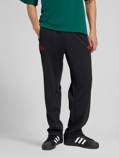 Mannelijk model draagt Regular Fit Sweatpants met katoen van adidas Originals, look: effen kleuren, regular fit pasvorm, gestikt logo, galonstrepen, boord: elastisch, materiaalverwerking: sweat. Ganzkörperansicht van voren.