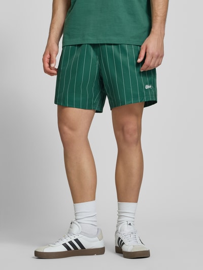 Mannenmodel draagt Shorts mit Streifenmuster und elastischem Bund van BLKVIS in regular fit met streepmotief, labelstitching, elastische band, bandwijdte maat M 36 cm, binnenbeenlengte maat M 15 cm, geheel in groentinten met witte strepen, detailopname benen