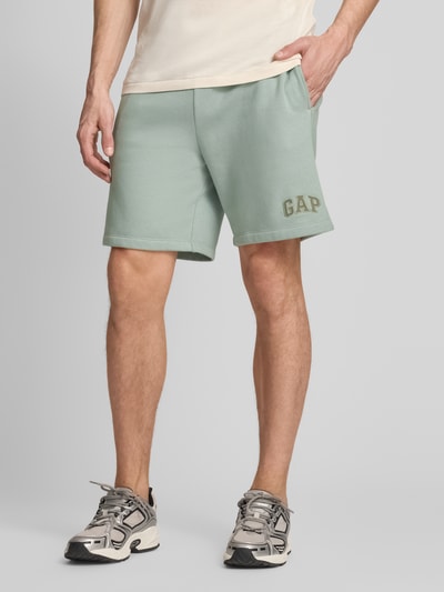 Männermodel trägt Sweatshorts mit Logo und elastischem Bund von GAP aus Baumwoll-Mix, Regular-Fit, Eingrifftaschen, mintgrün, Ganzkörperansicht von vorne.