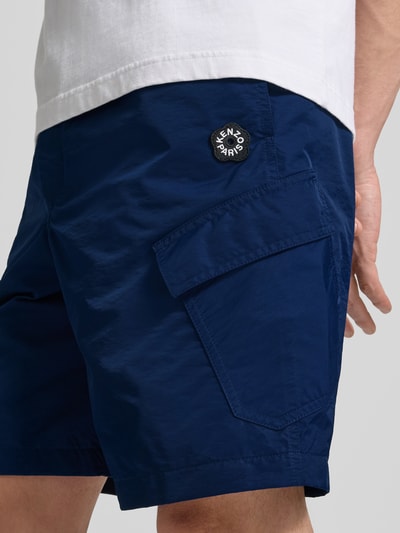 Männermodel trägt Regular Fit Shorts mit Cargotaschen von Kenzo in Dunkelblau, Baumwollstruktur, sichtbare Cargotasche, Nahaufnahme Oberschenkel. Innenbeinlänge 42 cm, Bundweite 24 cm, elastischer Bund mit Tunnelzug, Gesäßtaschen.