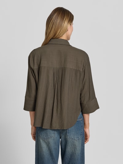 Frauenmodel trägt Regular Fit Bluse aus Viskose-Mix mit 3/4-Arm Modell 'Forna' von OPUS in Oliv, sichtbare Textur, Ganzkörperansicht Rückansicht, Hemdblusenkragen, verdeckte Knopfleiste, Brusttaschen, Rückenlänge 64 cm, Ärmellänge 40 cm bei Größe 36.