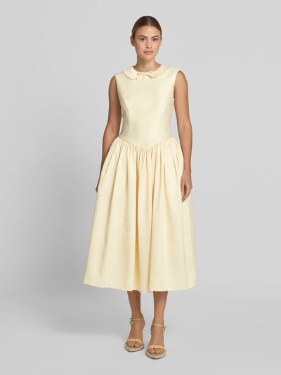 Frauenmodel trägt Midikleid mit Umlegekragen von Self-Portrait, taillierte Passform, Zierschleife, ausgestellte Passform, ärmelloses Design, zartgelbe Farbe, feine Textur, Gesamtlänge 127 cm, Brustweite 44 cm, Taillenweite 38 cm, Ganzkörperansicht von vorne.