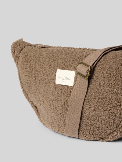 Produktfoto, Crossbody Bag aus Teddyfell mit Logo-Detail von Studio Noos in Braun, sichtbares Reißverschluss-Hauptfach, verstellbarer Schulterriemen, weiche Textur, Maße 40x22x11 cm, Schulterriemen 64 cm.