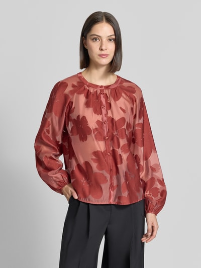 Modelka kobieca nosi Regular Fit Bluse mit Rundhalsausschnitt von Christian Berg Woman Selection, bawełniany miks, wzór allover, zapięcie na guziki, długość pleców w rozmiarze 36: 58 cm, długość rękawa w rozmiarze 36: 50 cm, odcień ceglany z kwiatowym wzorem, lekko połyskująca tekstura, widok na całą sylwetkę z przodu.