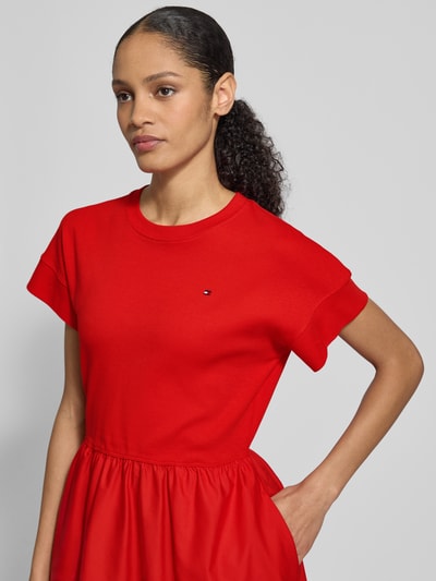 Vrouwenmodel draagt Ausgestelltes Freizeitkleid aus Material-Mix Modell 'CODY' van Tommy Hilfiger in effen rood katoenmix, logo-stiksel, ronde hals, korte mouwen, midi-lengte, zonder sluiting, detailopname bovenlichaam.