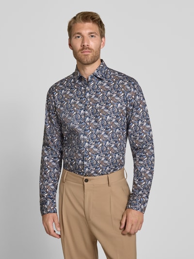 Männermodel trägt Businesshemd von Seidensticker mit blau-braunem Muster, beige Hose, Hintergrund einfarbig, Ganzkörperansicht von vorne. Herren Businesshemd von Seidensticker