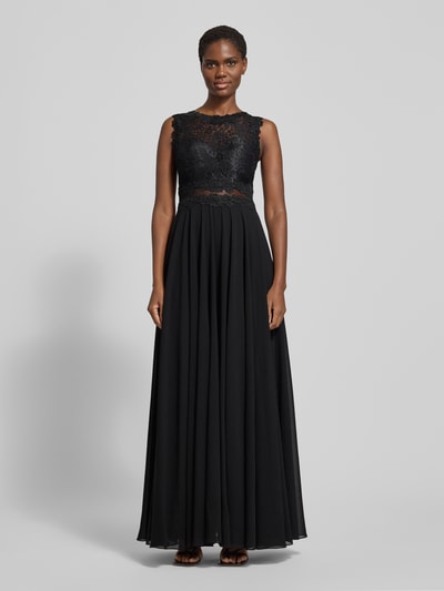 Frauenmodel trägt Abendkleid mit Spitze und Rundhalsausschnitt von Mascara, A-Linie, Maxikleid, Farbe Schwarz, detailreiche Textur am Oberteil, Rückenlänge bei Größe 36: 153 cm, Brustweite: 33 cm, Ganzkörperansicht von vorne.