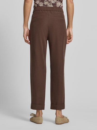 Frauenmodel trägt Stoffhose mit französischen Eingrifftaschen von Jake*s Collection, braun, Straight Fit, elastischer Bund, Gesäßleistentaschen, Saum mit fixiertem Aufschlag, Ganzkörperansicht Rückansicht.