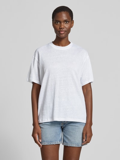 Vrouwenmodel draagt Regular Fit T-shirt uit zuiver linnen van Anine Bing, ronde hals, gestikt logo, korte mouw, ruglengte maat S 63 cm, wit, denim short, Ganzkörperansicht von vorne