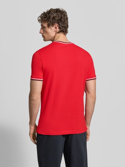 Mężczyzna model nosi T-Shirt mit Kontraststreifen und Rundhalsausschnitt von Christian Berg Men, bawełna z domieszką elastanu, krój regular fit, czerwony z białymi i granatowymi paskami, długość tyłu w rozmiarze M: 71 cm, widok całej sylwetki z tyłu.