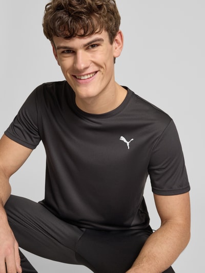 Męski model nosi T-Shirt z logo i okrągłym dekoltem od PUMA PERFORMANCE, kolor ciemnoszary, regular fit, zbliżenie na górną część ciała.