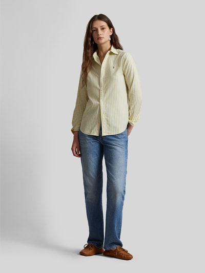 Frauenmodel trägt Regular Fit Hemdbluse aus reiner Baumwolle von Polo Ralph Lauren mit gelb-blauem Allover-Streifenmuster, Ganzkörperansicht von vorne.