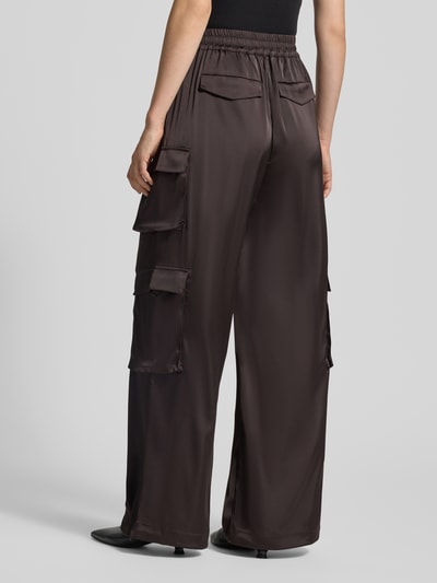 Frauenmodel trägt Loose Fit Stoffhose mit elastischem Bund Modell 'darzi' von Gestuz, dunkelbraun, Cargotaschen, Material-Mix mit Stretch-Anteil, Ganzkörperansicht Rückansicht.