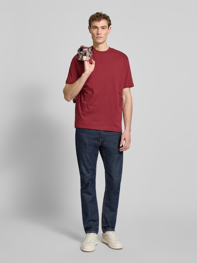 Männermodel trägt Regular Fit T-Shirt aus reiner Baumwolle von MCNEAL in Rot, kombiniert mit Jeans, Ganzkörperansicht von vorne.