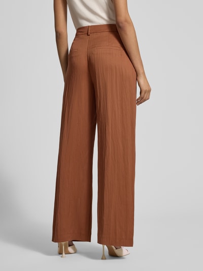 Frauenmodel trägt Stoffhose mit Eingrifftaschen und Gesäßleistentaschen von Jake*s Collection in Braun, Loose Fit, Ganzkörperansicht Rückansicht.
