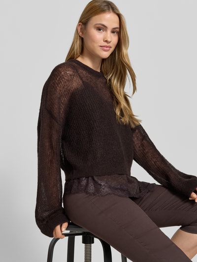 Frauenmodel trägt sommerlichen cropped Strickpullover - curated by Mary Braun von Style Icon Collection in Braun, Strick-Optik, Relaxed-Fit, Rundhalsausschnitt, elastische Abschlüsse, Rückenlänge bei Größe S 53 cm, Ärmellänge 72 cm, Ganzkörperansicht von vorne.