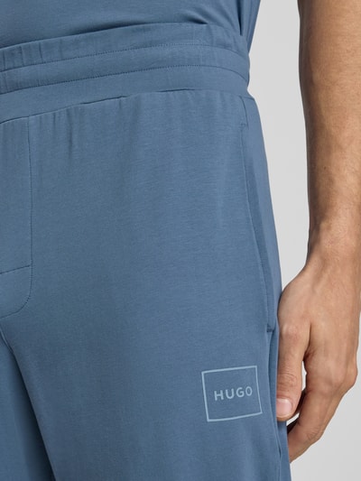 Männermodel trägt Regular Fit Sweathose aus Baumwoll-Mix Modell 'LAZE' von HUGO in Blau, unifarben, Label Print, Nahaufnahme Oberkörper.