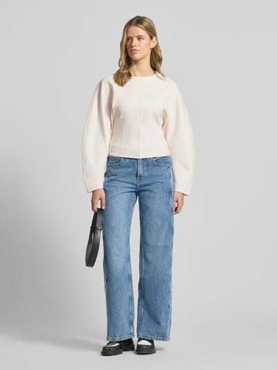 Kobiece model prezentuje Sweatshirt mit Rundhalsausschnitt od Gina Tricot, mieszanka bawełny z dodatkiem streczu, krój sculpted fit, okrągły dekolt, lekko zaokrąglony dół, jasny kolor, gładka tekstura, widok całej sylwetki z przodu.
