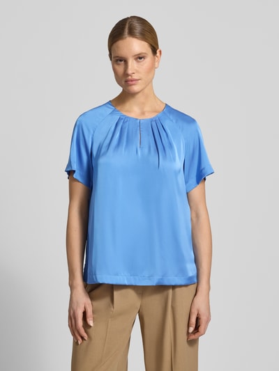 Frauenmodel trägt Blusenshirt aus Satin mit Rundhalsausschnitt von Comma in Blau mit Drapierungen, Regular-Fit, beige Hose, Ganzkörperansicht von vorne. Rückenlänge bei Größe 36: 60 cm, Ärmellänge bei Größe 36: 33 cm.