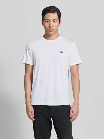 Männermodel trägt T-Shirt mit Logo-Patch und Rundhalsausschnitt von Emporio Armani in Weiß, Reine Baumwolle, Modern Fit, Rückenlänge 69 cm, Ganzkörperansicht von vorne.