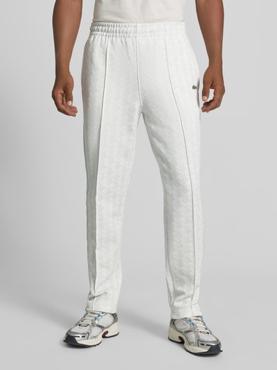 Männermodel trägt Regular Fit Sweathose mit Baumwoll-Anteil von Lacoste in Weiß mit dezentem Muster, Ganzkörperansicht von vorne. Herren Sweathose von Lacoste.