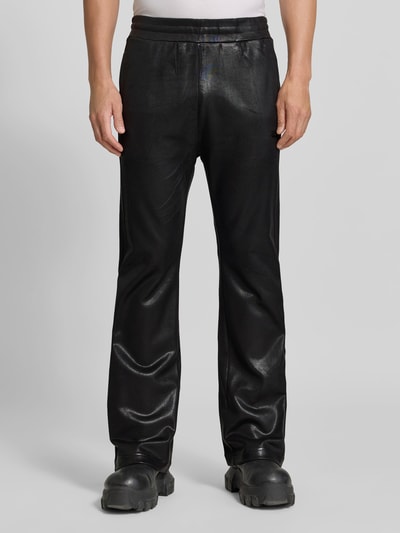 Männermodel trägt schwarze Flared Fit Hose aus Baumwoll-Mix von Diesel mit Leder-Optik, Gesäßtasche, elastischem Bund, Ganzkörperansicht von vorne.