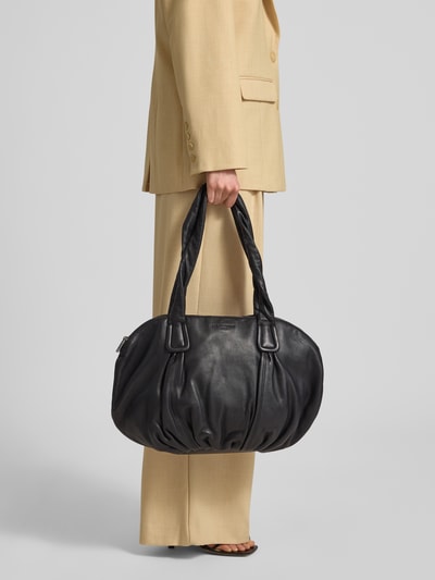 Frauenmodel trägt Shopper aus echtem Leder mit Logo-Prägung Modell 'Lucy' von LIEBESKIND BERLIN in Schwarz, texturierte Oberfläche, Ganzkörperansicht von vorne. Hauptfach mit Reißverschluss, Tragehenkel, Maße: Breite 46 cm, Länge 31 cm, Tiefe 16 cm, Schulterriemen 66 cm.