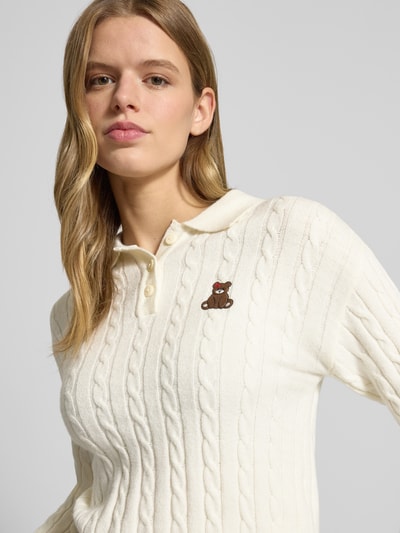 Frauenmodel trägt Slim Fit Poloshirt aus Viskose-Mix Modell 'KATIA' von Only, Optik: Unifarben, Zopfmuster, Stickerei, Strick, Nahaufnahme Oberkörper.