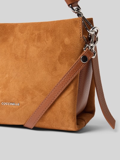 Produktfoto, Torebka z zamszową teksturą w kolorze brązowym, detal z logo, Model 'BOHEME' od Coccinelle, główna przegroda z zamkiem błyskawicznym, uchwyt, odpinany pasek na ramię, przegródka wewnętrzna zapinana na zamek błyskawiczny, szerokość 25 cm, długość 19 cm, głębokość 13 cm, długość paska na ramię 127 cm.