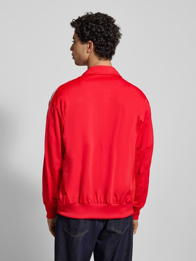 Männermodel trägt Sweatjacke mit Stehkragen von adidas Originals, czerwona, regular fit, materiał mix, widoczny stehapel, ribbany dół i rękawy, widok na całe plecy, Ganzkörperansicht Rückansicht.