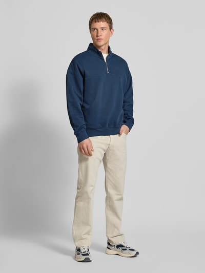 Männermodel trägt dunkelblaues Sweatshirt mit Reißverschluss Modell 'MARINA QUARTER ZIP' von Levi's®, gerade geschnitten, Stehkragen, Baumwolle, helle Hose, Ganzkörperansicht von vorne.