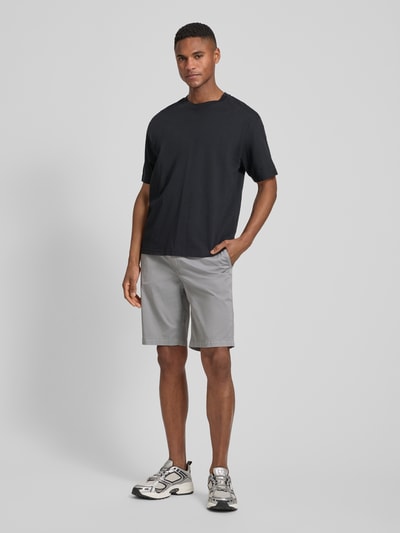 Männermodel trägt Tapered Chinoshorts aus Baumwoll-Mix von BOSS Orange in Optik: Unifarben, Materialverarbeitung: Twill, Ganzkörperansicht von vorne.