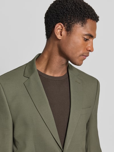 Männermodel trägt olivgrünes Slim Fit Sakko mit Woll-Anteil Modell 'SLIM-NEIL' von Selected, feine Stoffstruktur, Nahaufnahme Oberkörper.
