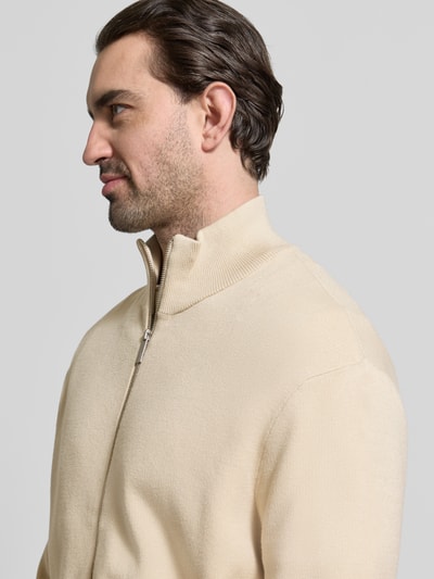 Männermodel trägt Relaxed Fit Strickjacke aus Viskose-Mix Modell 'TELLER' von SELECTED HOMME in Beige, Feinstrick, Nahaufnahme Oberkörper.