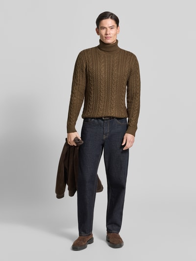 Männermodel trägt Slim Fit Strickpullover mit Baumwoll-Anteil Modell 'Callum' von JACK & JONES, Zopfmuster, dunkelbraun, Ganzkörperansicht von vorne.