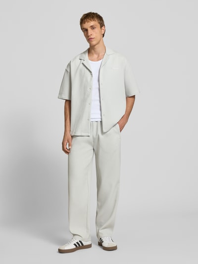 Męski model nosi Sweatpants mit Strukturmuster und elastischem Bund od Pegador, jasnoszary, materiał z domieszką stretchu, krój relaxed fit, widok całej sylwetki z przodu.