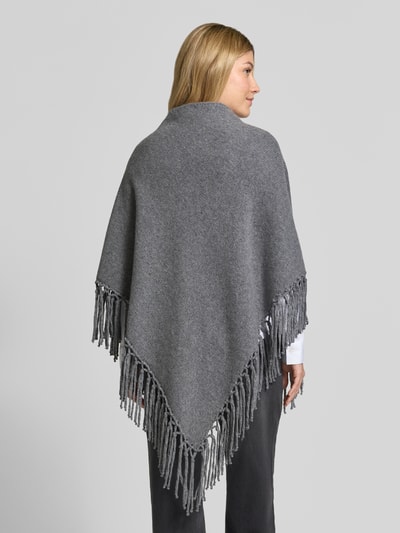 Vrouwenmodel draagt grijze poncho uit pure scheerwol met franjes, model 'TORNADO' van Weekend Max Mara, dames poncho, volledige achteraanzicht.