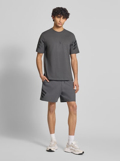 Männermodel trägt Relaxed Fit T-Shirt aus reiner Baumwolle von adidas Sportswear in Optik: Unifarben mit Logo-Print, Rundhals, Kurzarm, Jersey, Ganzkörperansicht von vorne.